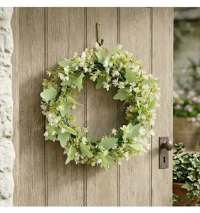 Détail d'une couronne florale printemps-été avec feuilles d'eucalyptus et petites fleurs blanches
