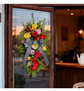 Guirnalda de flores artificiales con lazo a rayas colgada en una puerta de cristal