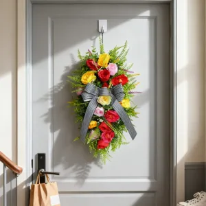 Corona de flores artificiales con gran lazo a rayas blancas y negras en la puerta