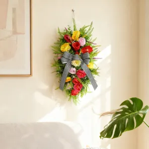 Corona floral de lágrima con lazo grande a rayas colgada en la pared interior de la casa
