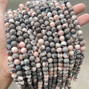 Macro view of natural zebra stone round beads showing unique pink and grey textures.