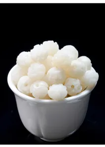 Detailed view of hand-carved white bodhi root lotus beads presented in a ceramic bowl.