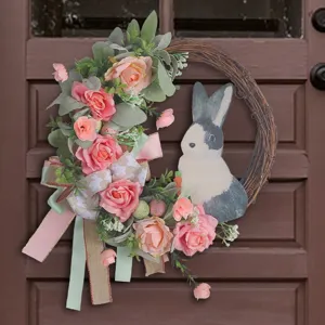 Easter wreath with pink roses and rabbit decoration hanging on a brown wooden door