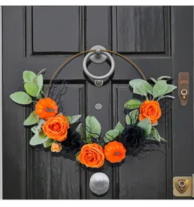 Halloween metal hoop wreath decorated with orange pumpkins and black roses on a black door