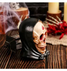 Vista detallada de una figura de calavera de Halloween de resina con capucha negra en mesa rústica