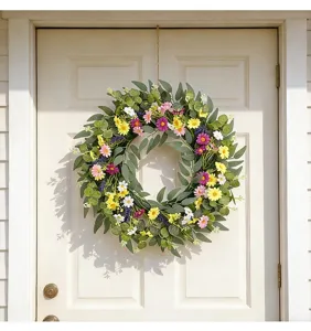 Vue détaillée d'une couronne de fleurs sauvages printanière sur une porte blanche.