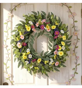 Détail d'une couronne de fleurs sauvages artificielles printanière sur porte blanche
