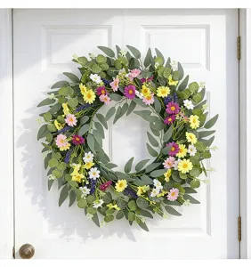 Vue détaillée d'une couronne de fleurs sauvages printanières sur une porte blanche