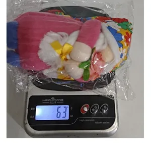 Sunflower gnome plush doll weight measurement showing 63g on a digital kitchen scale