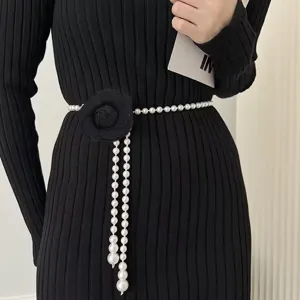 Elegant pearl waist chain with a black camellia flower on a black ribbed dress