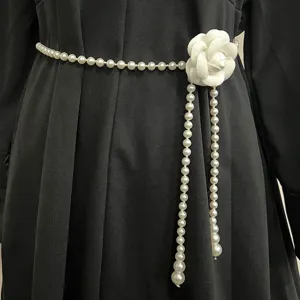 Close-up detail of an elegant white camellia pearl waist chain accessory for dresses.