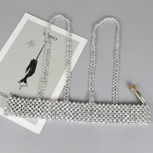 Detail of silver beaded harness belt with reflective metallic beads on grey surface.