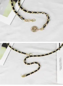 Nahaufnahme des eleganten goldfarbenen Kettengürtels mit Ledergeflecht und Sonnenanhänger.