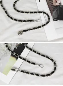 Detailaufnahme des geflochtenen Leder- und Metallketten-Gürtels mit Rosen- und Schlossanhänger.
