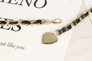 Nahaufnahme einer goldfarbenen Taillenkette mit schwarzem Leder und Herzanhänger.