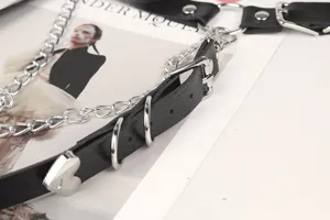 Dettaglio della cintura punk gotica in pelle nera con borchia a cuore e catene d'argento