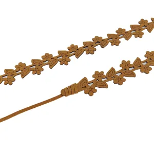 Detail van de smalle microvezel riem met gebloemd ontwerp en strikkoord voor dames.