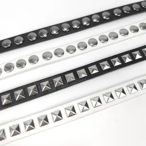 Detailed view of black and white skinny belts with round and square silver studs.