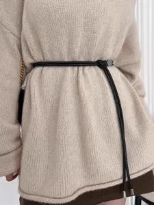 Detailed view of thin black leather cord belt with metal accents on a beige knit sweater