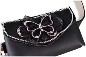 Macro detail showing the sparkling rhinestone butterfly bow on a black leather waist bag