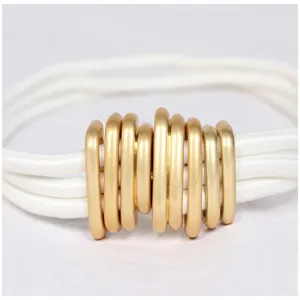 Detailed macro view of vintage caterpillar gold metal buckle on white elastic waist belt