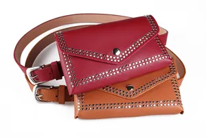 Detail of punk style rivet waist bags in red and tan leather with silver buckles.