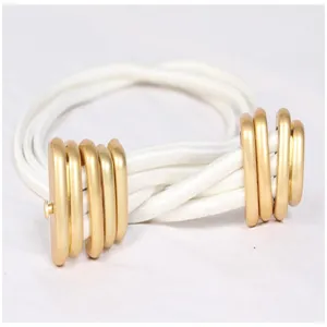 Close-up view of a retro white elastic waist belt featuring textured gold metal ring buckles.