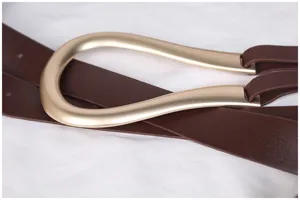 Vue macro détaillée de la boucle en fer à cheval dorée sur une ceinture en cuir marron