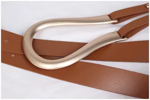 Gros plan sur une boucle en métal doré en forme de U sur une ceinture en cuir marron.