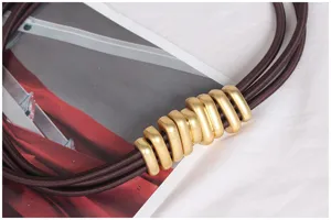 Close-up of retro waist belt featuring matte gold caterpillar buckle and brown bands.