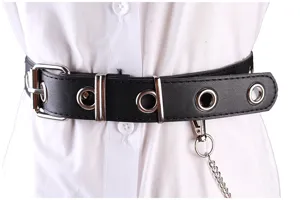 Close-up detail of black punk belt with silver grommets and hanging decorative metal chain