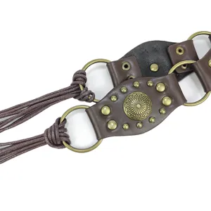 Close-up detail of a vintage leather belt featuring bronze rivets and a sun medallion