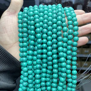 Detailed macro view of synthetic turquoise round beads with black veins held in hand
