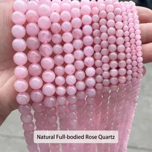 Primo piano di perle in quarzo rosa naturale di varie dimensioni per gioielli fai-da-te