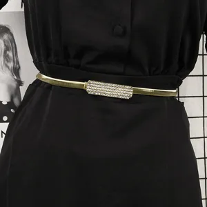 Detailed view of elegant gold elastic metal belt with a sparkling rhinestone buckle