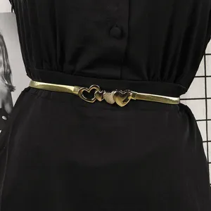 Close-up of an elegant gold elastic metal belt with heart buckle on a black dress