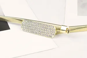 Close-up of gold elastic metal chain belt with sparkling rhinestone buckle detail.