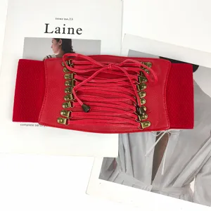 Close-up of red wide elastic corset belt with lace-up tassels and bronze hardware