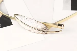 Detailed close-up view of a golden leaf-shaped metal buckle on a flexible elastic thin belt