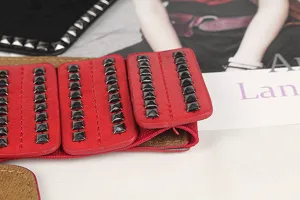 Detail of red leather corset belt with black square rivets and elastic band