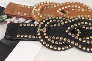 Close-up of punk style elastic waist belts with golden rivets in black and brown