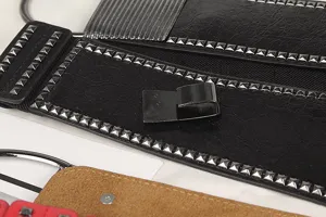 Close-up of punk style wide elastic waist belt with silver square rivets and leather texture.