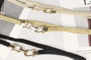 Primer plano de elegantes cinturones elásticos para mujer en tres colores con hebillas doradas.