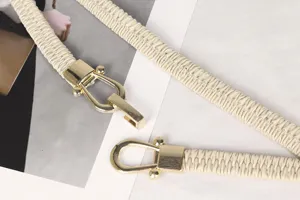 Primer plano de un cinturón elástico crema con hebilla dorada en forma de herradura.