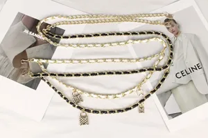 Detail view of gold multi-layered waist chain with interwoven leather and padlock charms