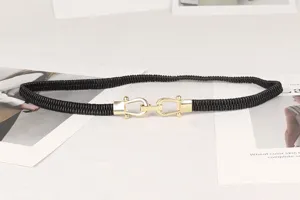 Primer plano de un cinturón elástico negro con una elegante hebilla dorada entrelazada