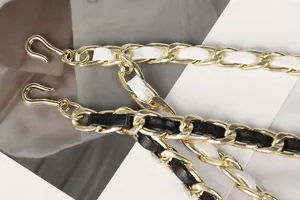 Close-up of a gold double-layer woven chain waist belt with black and white leather strips.