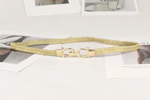 Detalle de un cinturón elástico dorado con una elegante hebilla metálica en forma de U