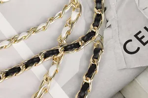 Detail showing gold chain belt with black and white woven leather strips for women.