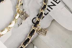 Close-up of double-layer metal chain belt with woven leather and lock charms
